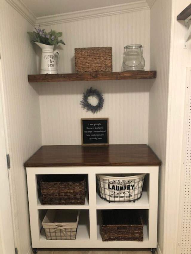 The finished four-cubby laundry cabinet beneath the long wood shelf