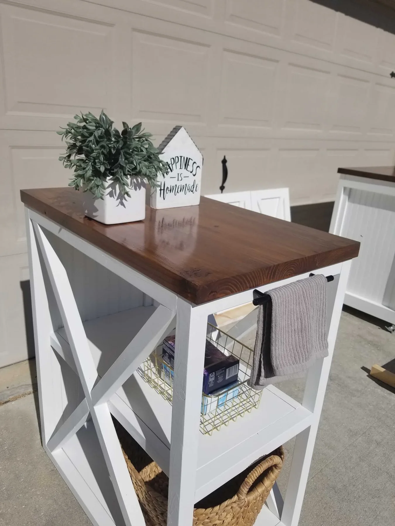 The finished X-braced rolling laundry cabinet with a wood top, towel bar, baskets and casters