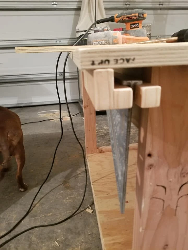 A clamp hanging from a small wooden holder on the workbench side